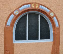 Zugemauertes Renaissanceportal mit geschmückten Rahmen, der in Kreisornamenten Zeichen der Bäckerzunft (links Brotlaib, rechts Brezel) aufweist.