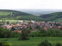 Das Foto zeigt das Dorf Weiler bei Bingen in der Talsenke zwischen Hügeln und Bergen. Aufgenommen aus größerer Entfernung.