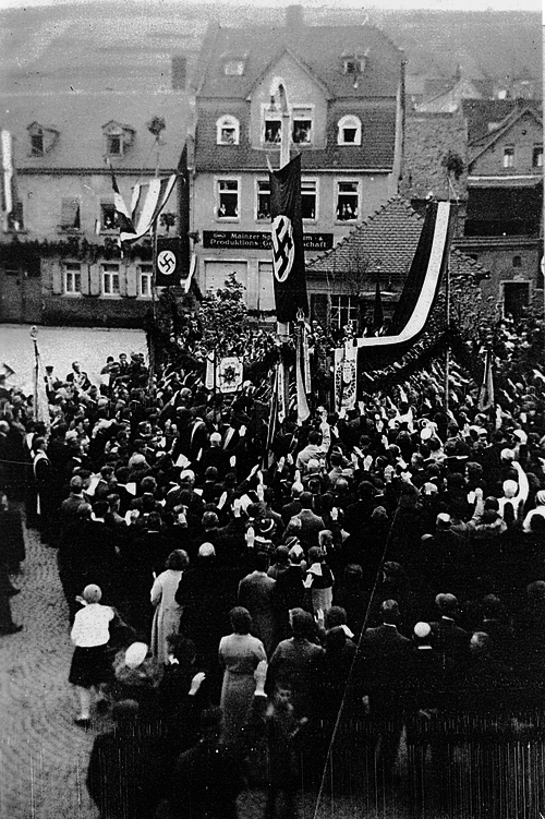 Abb. 5: Pflanzung der Hitler-Eiche mit zahlreichen Vereinsfahnen, im Hintergrund das Haus der Mainzer Spar-, Konsum- und Produktions-Genossenschaft.