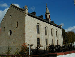 Die evangelische Kirche Gau-Weinheim wurde 1863/64 als Rechtecksaal im Rundbogenstil und historisierenden Motiven errichtet.