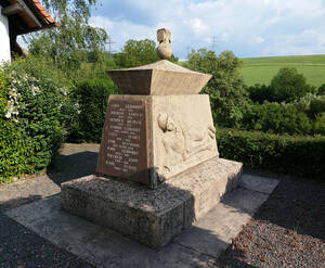 Das Kriegerdenkmal in Wörsbach, 1920er Jahre. Steinaltar mit Sarg, der von einer Kugel mit "Eisernem Kreuz" bekrönt wird. An der Vorderseite Relief eines liegenden deutschen Soldaten, der mit der linken Hand den Lauf eines Gewehrs umfasst. An drei Seiten Gedenktafeln mit Namen und Lebensdaten der Gefallenen und Vermissten der Weltkriege.