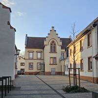 Das alte Schulhaus neben der Kirche ist ein zweigeschossiger, traufständiger Putzbau mit Satteldach in neuklassizistischen und historisierendem Stil. Es ist mit der Jahreszahl 1874 bezeichnet. Das Bild zeigt das Gebäude vom Kirchplatz der benachbarten St. Peterskirche aus.