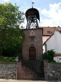 Der protestantische Glockenturm in Wörsbach, erbaut 1902. Ein Sandsteinquaderbau mit offenem Stahlgerüst, in dem die Glocken untergebracht sind, das von einem Kupferdach mit Wetterhahn bekrönt wird.
