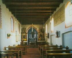 Das Foto zeigt den Innenraum der romanischen Kirche St. Peter. Blick über die Bankreihen hinweg in den Chor mit barocken Altären. Der Raum besitzt nur eine Balkendecke,